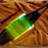 Une bouteille verte lumineuse, peut-être la bière la plus chère du monde, est présentée dans un écrin de tissu doré.