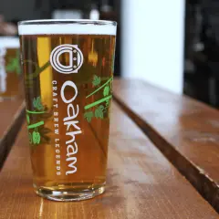 Verre de bière blonde Oakham sur table en bois. Le taux de sulfate dans l'eau est idéal pour cette boisson artisanale.