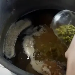 Ajout de houblon dans la cuve de brassage. Le houblon, essentiel pour l'amertume et les arômes de la bière, est versé dans le moût bouillant.