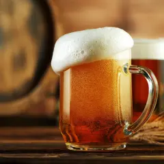 Deux chopes de bière dorée, mousseuse, près d'un tonneau. Une bière disparue, mais le plaisir reste.