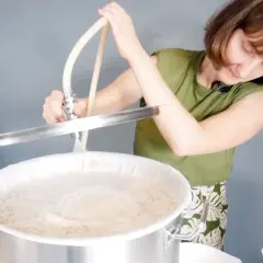 Une femme prépare une recette d'IPA, versant un liquide dans une cuve de brassage.