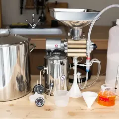 Matériel pour fabriquer sa bière : cuve, moulin à grains, fermenteur, entonnoirs et éprouvette graduée.