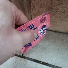 Main tenant une étiquette rose, peut-être de levure périmée 1 an, avec une illustration de femme.