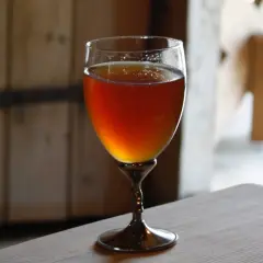 Verre de bière norvégienne ambrée, posé sur une table en bois.