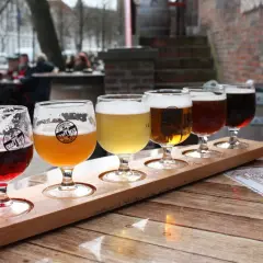 Dégustation de bières artisanales dans un bar. Cinq verres de différentes couleurs sur un plateau en bois.