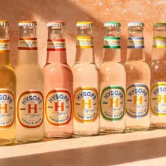 Sept bouteilles de bière et de tonic Hysopé alignées, avec des saveurs comme le gingembre et le pamplemousse, évoquant un apéritif en Italie.