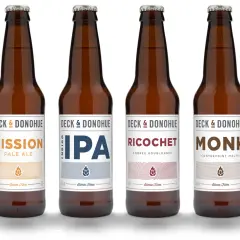 Six bouteilles de bière de la marque Deck & Donohue, proposant différents types de bière : Trouble, Mission, IPA, Ricochet, Monk et Saison.