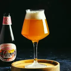 Une bouteille et un verre de bière ambrée Anchor, avec une mousse généreuse. L'étiquette de la bière mentionne "Anchor Brewing".