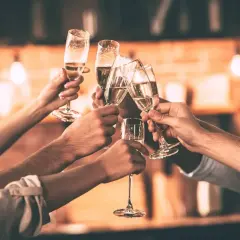 Des mains lèvent des flûtes de champagne pour trinquer. Une belle façon de célébrer, comme pour apprendre comment trinquer en allemand avec un "Prost !".
