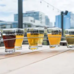 Un assortiment de bières, dont une délicieuse sour ale, sur une table en bois avec des bâtiments en arrière-plan.