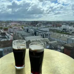 Deux bières Guinness sur une table dorée, avec une vue panoramique sur Dublin.