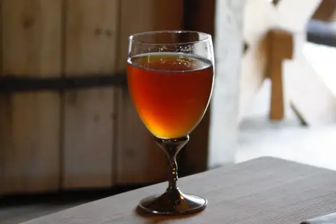 Verre de bière norvégienne ambrée, posé sur une table en bois.