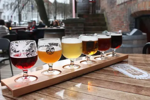Dégustation de bières artisanales dans un bar. Cinq verres de différentes couleurs sur un plateau en bois.