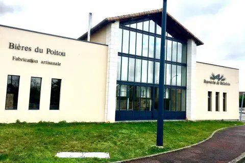 Bâtiment moderne de la Brasserie de Bellefois, spécialisée en bières du Poitou. L'enseigne "Bières du Poitou" est visible, ainsi que le logo de la brasserie.