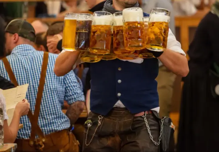 Un serveur porte plusieurs chopes de bière mousseuse lors de l'October Fest.