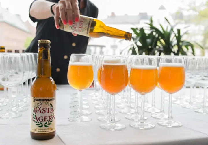 Une personne verse la bière suédoise connue, Bästa Lagern, dans des verres.