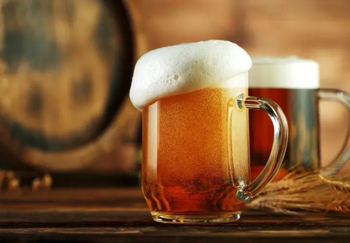 Deux chopes de bière dorée, mousseuse, près d'un tonneau. Une bière disparue, mais le plaisir reste.