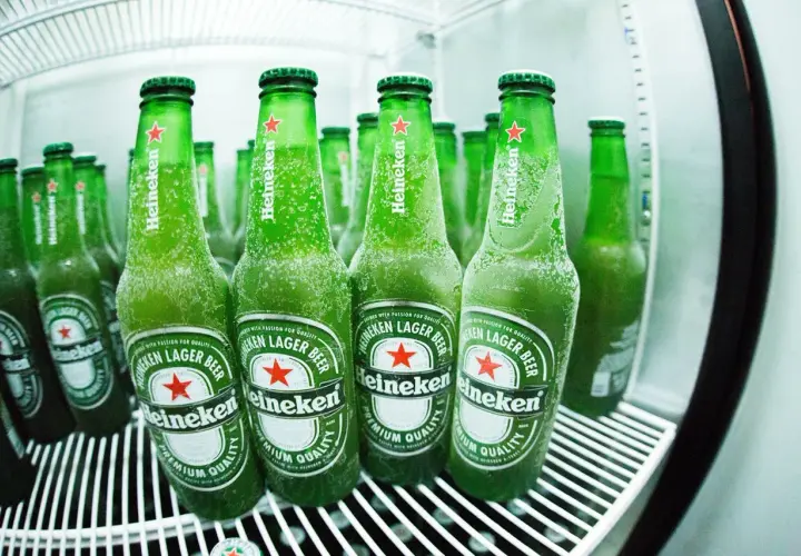 Des bouteilles de bière Heineken, givrées et prêtes à être dégustées, évoquant l'origine et la fraîcheur de la marque.