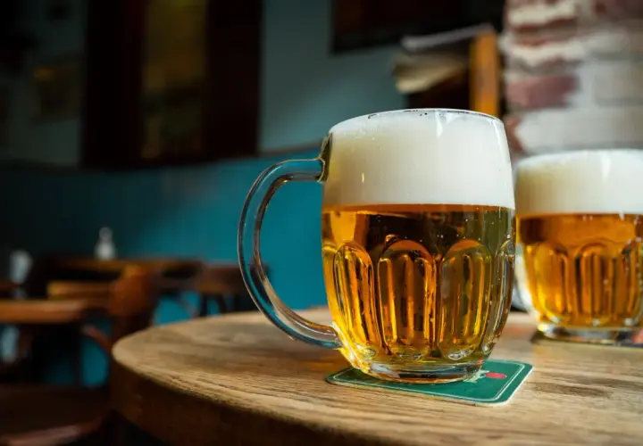 Deux chopes de bière pression mousseuse sur une table en bois. Le prix d'une bière pression est raisonnable pour ce moment de détente.