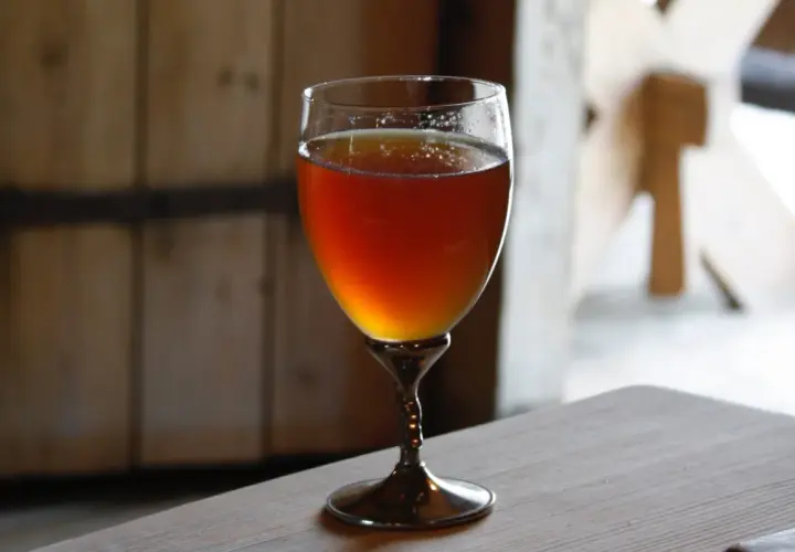 Verre de bière norvégienne ambrée, posé sur une table en bois.