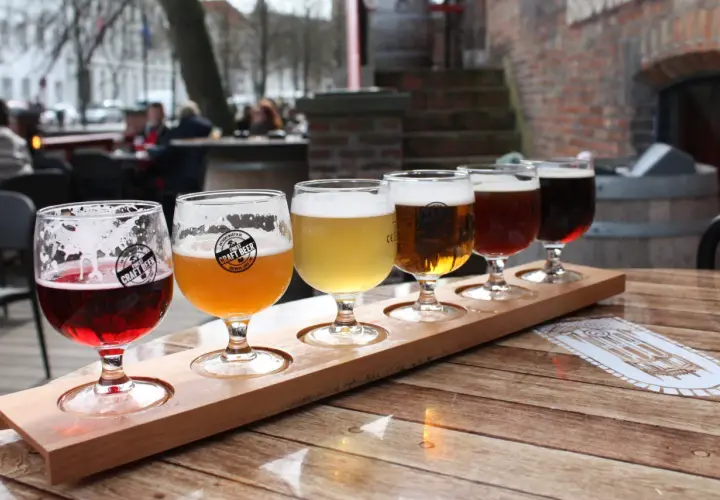 Dégustation de bières artisanales dans un bar. Cinq verres de différentes couleurs sur un plateau en bois.