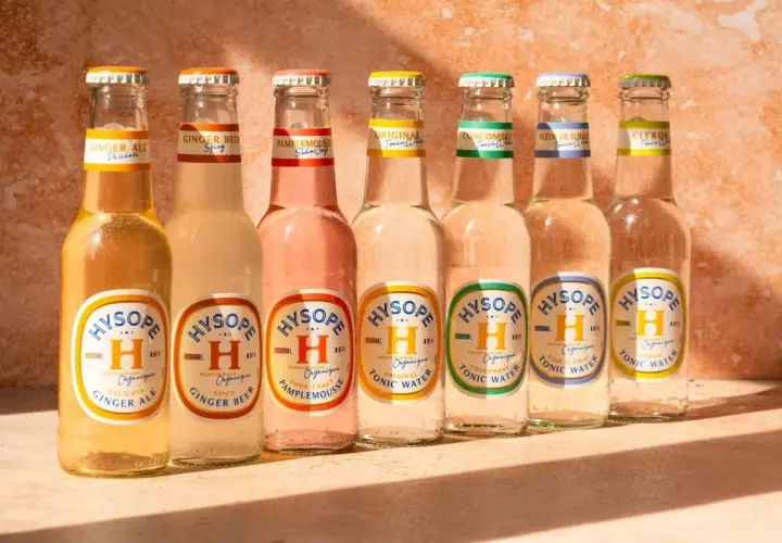 Sept bouteilles de bière et de tonic Hysopé alignées, avec des saveurs comme le gingembre et le pamplemousse, évoquant un apéritif en Italie.
