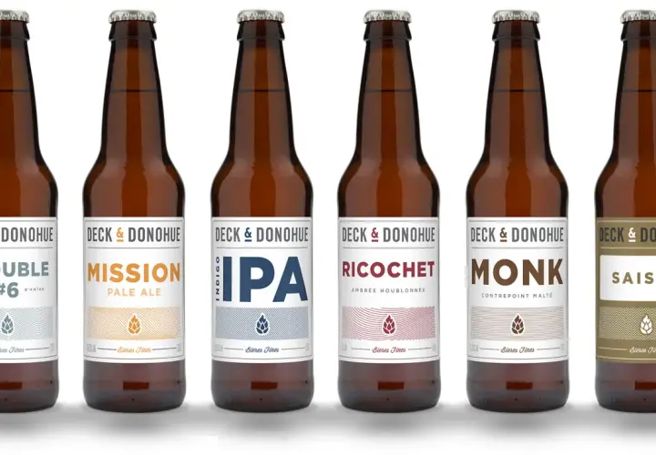 Six bouteilles de bière de la marque Deck & Donohue, proposant différents types de bière : Trouble, Mission, IPA, Ricochet, Monk et Saison.