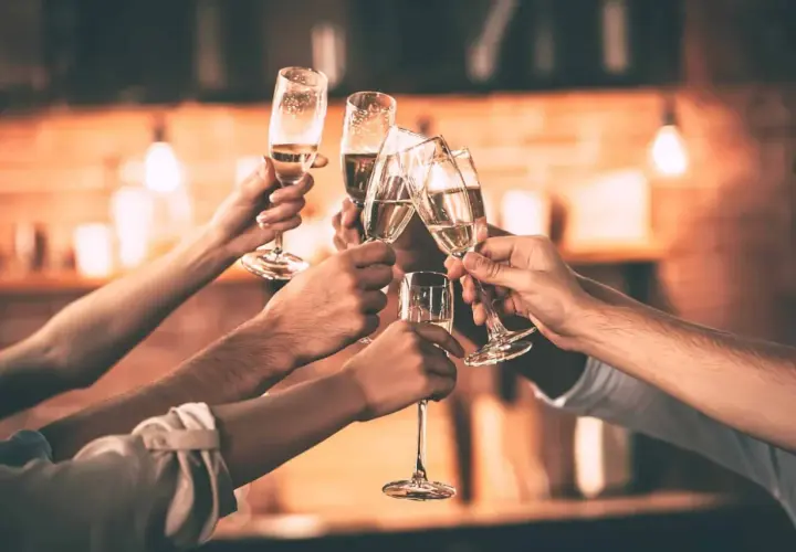 Des mains lèvent des flûtes de champagne pour trinquer. Une belle façon de célébrer, comme pour apprendre comment trinquer en allemand avec un "Prost !".