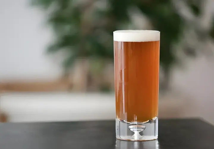 Un verre de bière ambrée, parfaite pour une recette de pale ale maison. La mousse blanche couronne la boisson.