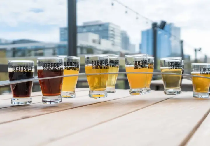 Un assortiment de bières, dont une délicieuse sour ale, sur une table en bois avec des bâtiments en arrière-plan.