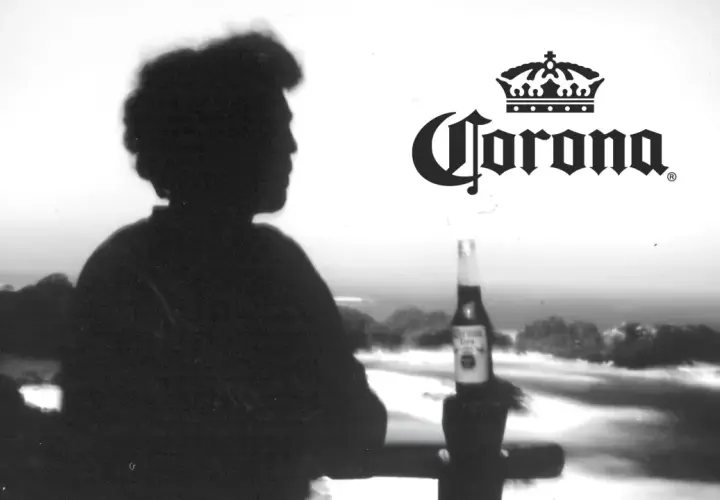 Silhouette d'une personne contemplant la mer, une bouteille de bière Corona à la main. L'image évoque l'origine de la bière Corona.