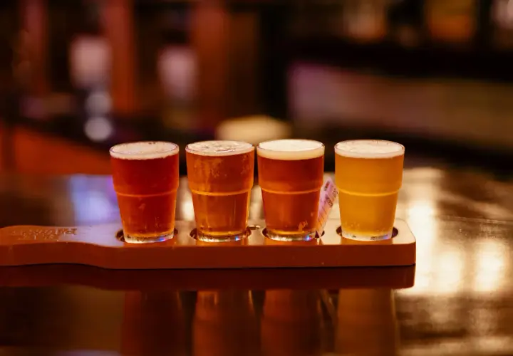 Quatre verres de bière, dont une rye IPA, sur un plateau en bois.