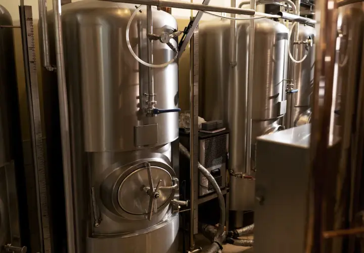 Cuves en acier inoxydable pour la fermentation de bière, avec manomètres et vannes. La température est cruciale pour une bonne fermentation.
