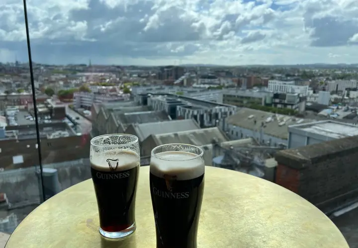 Deux bières Guinness sur une table dorée, avec une vue panoramique sur Dublin.