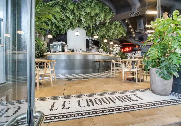 Entrée de la brasserie française "Le Choupinet", décorée de verdure luxuriante et d'un bar moderne.