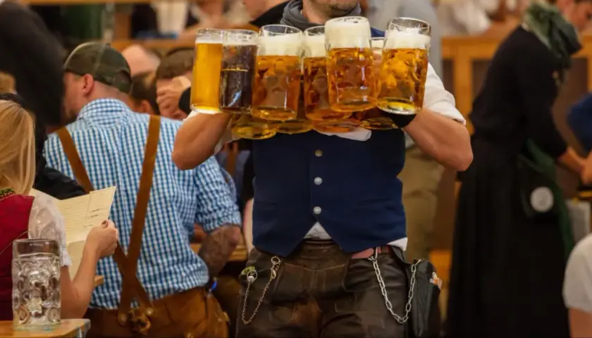Un serveur porte plusieurs chopes de bière mousseuse lors de l'October Fest.