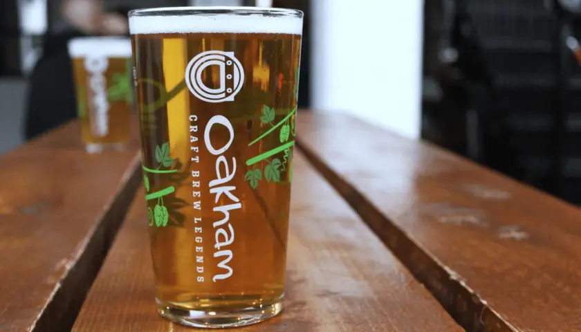 Verre de bière blonde Oakham sur table en bois. Le taux de sulfate dans l'eau est idéal pour cette boisson artisanale.