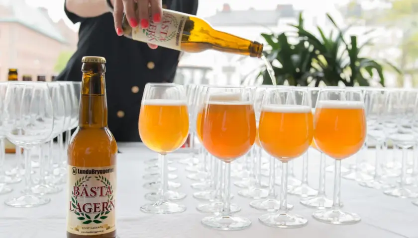 Une personne verse la bière suédoise connue, Bästa Lagern, dans des verres.
