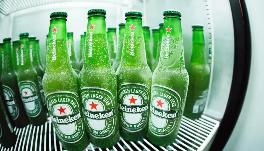 Des bouteilles de bière Heineken, givrées et prêtes à être dégustées, évoquant l'origine et la fraîcheur de la marque.