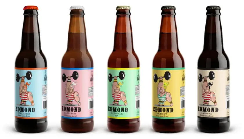 Cinq bouteilles de bière algérienne Edmond, aux étiquettes colorées représentant un haltérophile musclé.