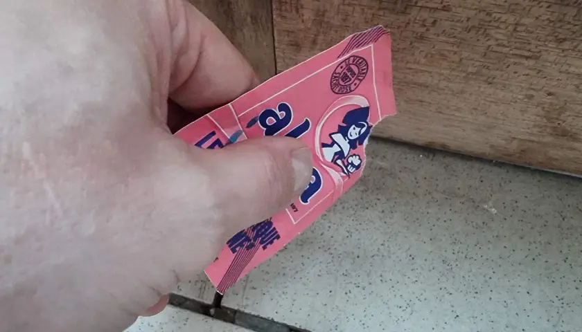Main tenant une étiquette rose, peut-être de levure périmée 1 an, avec une illustration de femme.