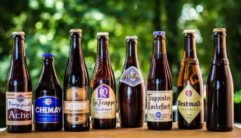Une sélection de 7 bières trappistes belges alignées : Achel, Chimay, Gregorius, La Trappe, Orval, Rochefort, Westmalle.