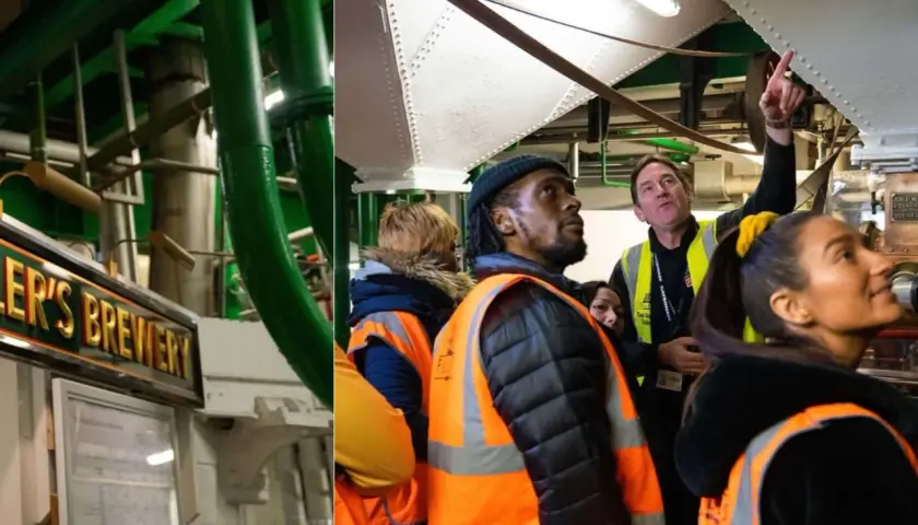 Visite guidée dans une brasserie londonienne. On aperçoit le panneau "Fuller's Brewery" et des visiteurs curieux observant les installations.