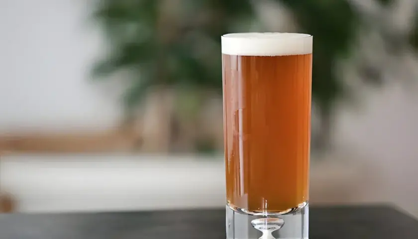 Un verre de bière ambrée, parfaite pour une recette de pale ale maison. La mousse blanche couronne la boisson.