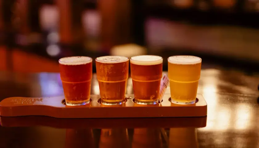 Quatre verres de bière, dont une rye IPA, sur un plateau en bois.
