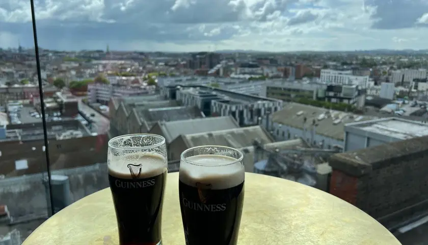 Deux bières Guinness sur une table dorée, avec une vue panoramique sur Dublin.