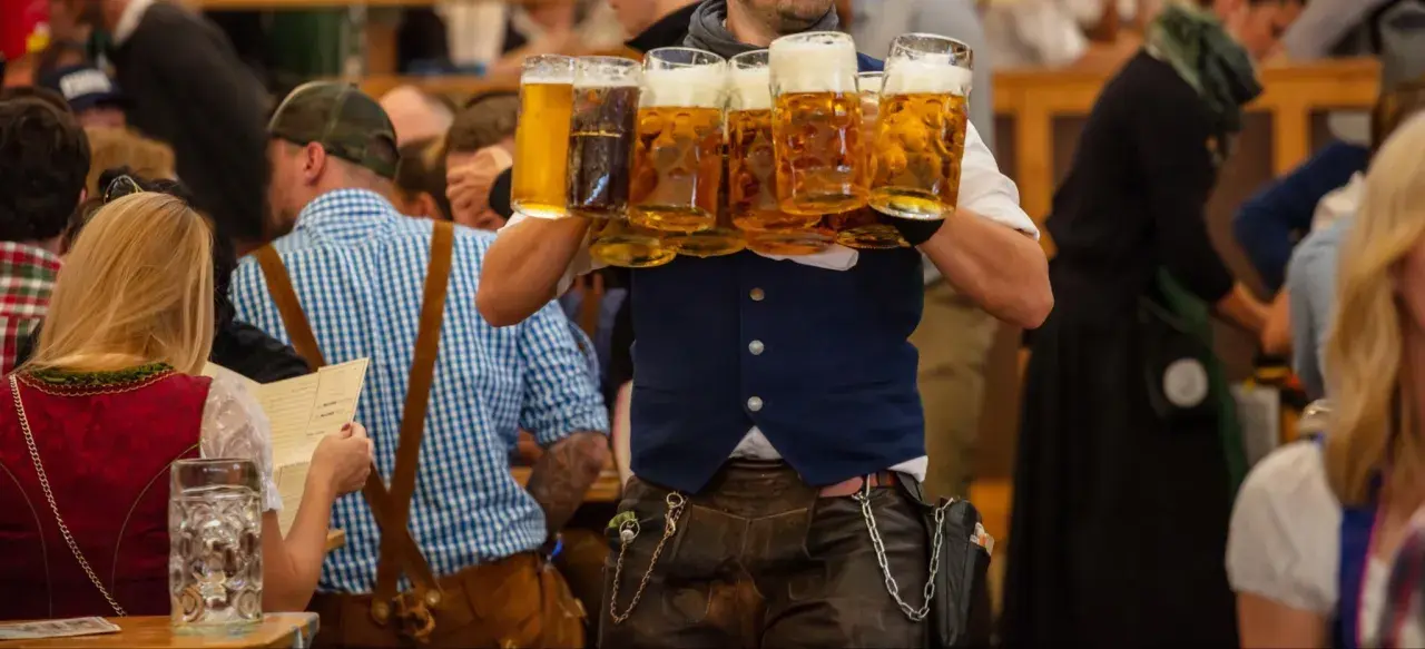 Un serveur porte plusieurs chopes de bière mousseuse lors de l'October Fest.