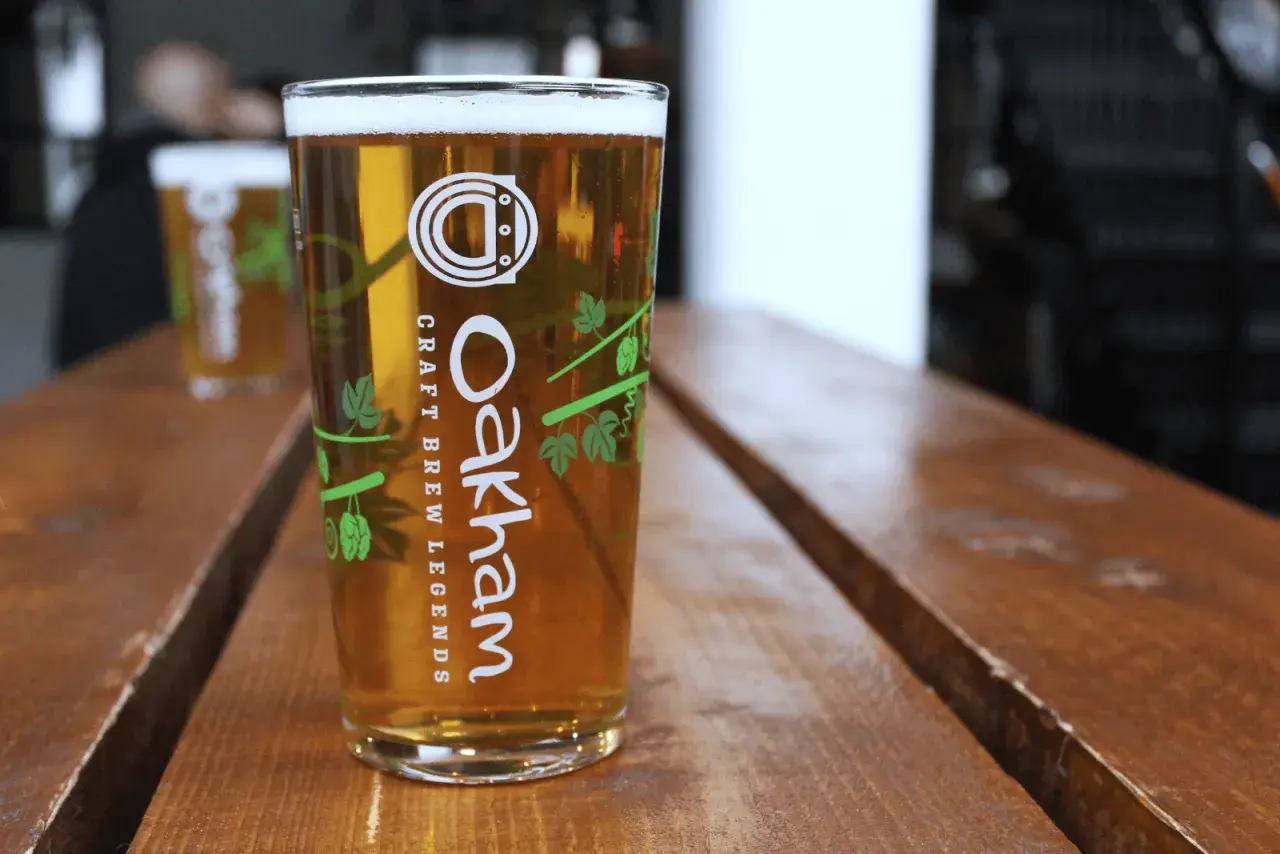 Verre de bière blonde Oakham sur table en bois. Le taux de sulfate dans l'eau est idéal pour cette boisson artisanale.