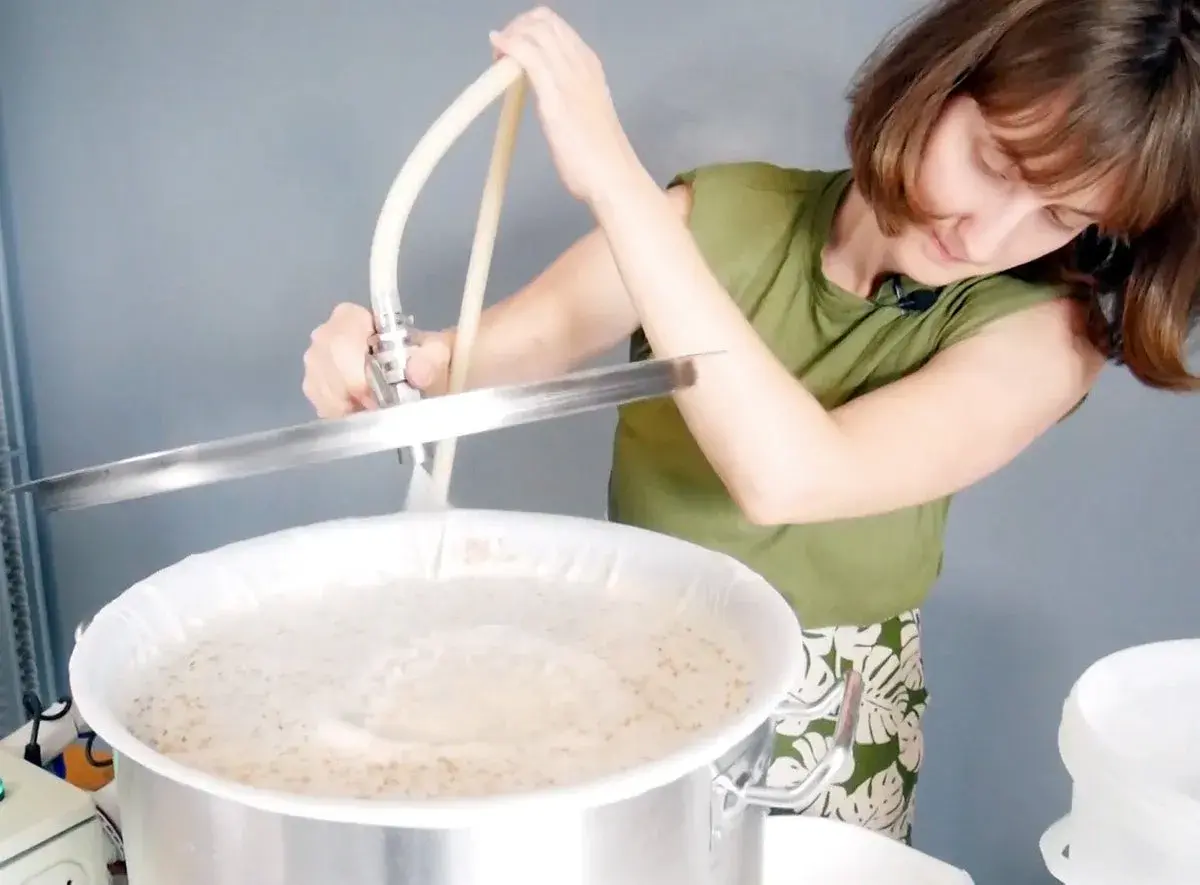 Une femme prépare une recette d'IPA, versant un liquide dans une cuve de brassage.