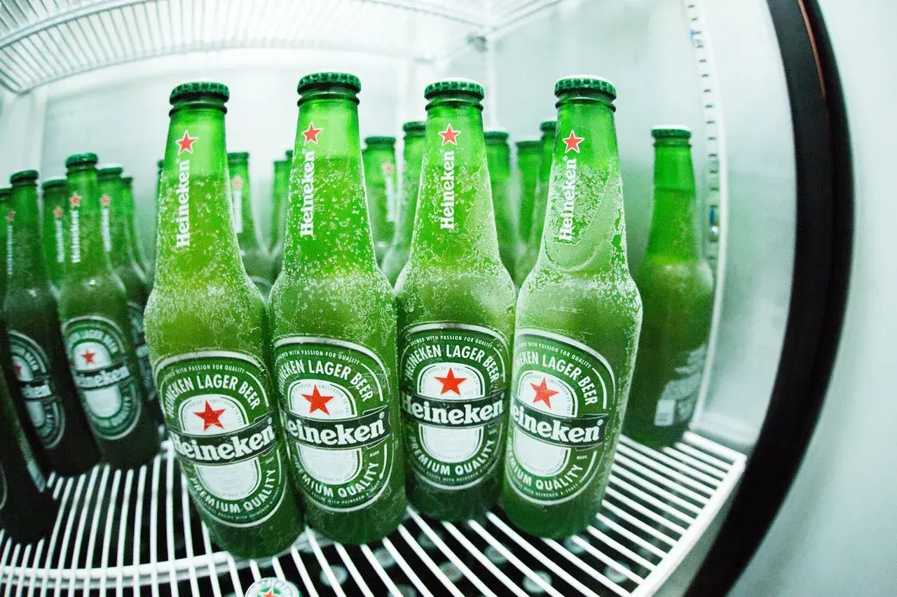 Des bouteilles de bière Heineken, givrées et prêtes à être dégustées, évoquant l'origine et la fraîcheur de la marque.